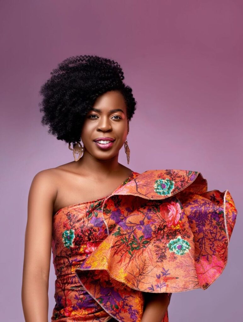 Lorna Zita com vestido cor de laranja e um fundo rosa
